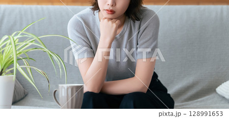 リビングのソファに座って考える女性 128991653