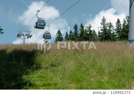 21 July 2025, Cerna Hora in Janskie Lazne, Czech Republic. Cableway System on Cerna Hora mountain. A beautiful sunny summer day. Cabin lift visible from the meadow. 128992373
