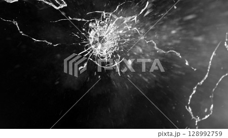 Close-up of gunshot through the glass, shattering against the black background Close-up of gunshot through the glass, shattering against the black background 128992759