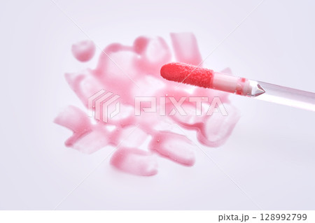 A pink lip gloss brush with a texture on the background. A pink lip gloss brush with a texture on the background. 128992799