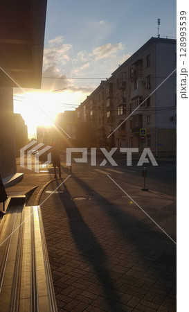 Golden Hour City Street with Silhouetted Pedestrians and Buildings 128993539