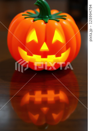 Glowing jack-o'-lantern on wooden table 128994794
