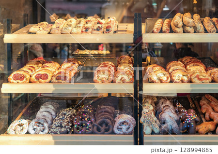 Assorted pastries, pretzels and sweet treats displayed in bakery window during festive winter market. Concept of pastry variety, fresh baked goods, delicious display baked goods Assorted pastries, pretzels and sweet treats displayed in bakery window during festive winter market. Concept of pastry variety, fresh baked goods, delicious display baked goods 128994885