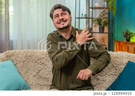 Middle-aged man gripping sore shoulder grimaces pain injury discomfort muscle strain seeking relief Middle-aged man gripping sore shoulder grimaces pain injury discomfort muscle strain seeking relief 128994910