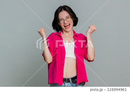 Young woman celebrating win with joyful smile expressing happiness success achievement excitement 128994961