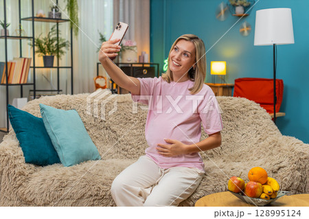Pregnant woman video calling husband turns smartphone to show belly smiling proudly about baby news Pregnant woman video calling husband turns smartphone to show belly smiling proudly about baby news 128995124