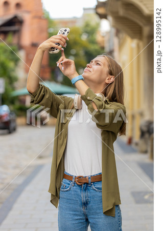 Young tourist woman trying to catch a communication signal and Internet on mobile phone on street Young tourist woman trying to catch a communication signal and Internet on mobile phone on street 128995142