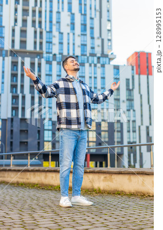 Mature man tourist with arms outstretched meditating with closed eyes standing on downtown street Mature man tourist with arms outstretched meditating with closed eyes standing on downtown street 128995153