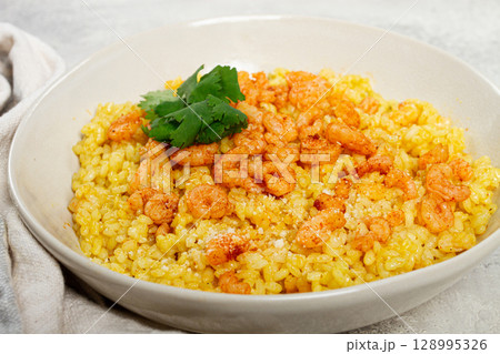 risotto with shrimp, in a bowl, on a textured surface, with a side dish of fresh coriander, homemade, no people, 128995326