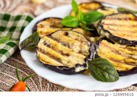 Juicy eggplant slices on a white plate, rustic serving Juicy eggplant slices on a white plate, rustic serving 128995618
