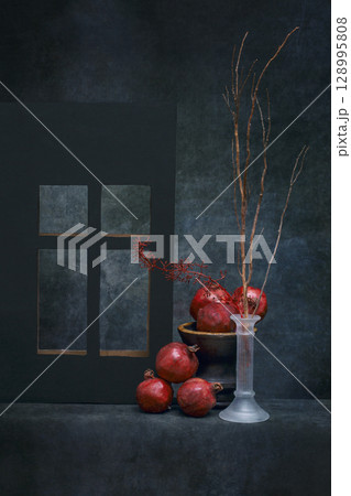 Still life with ripe pomegranates and a branch in a vase by the window 128995808