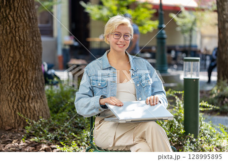 European young woman freelancer in city street closes laptop screen finishing working online job European young woman freelancer in city street closes laptop screen finishing working online job 128995895