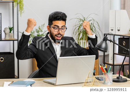 Business man winner working browsing typing on laptop at office celebrate big lottery win good news Business man winner working browsing typing on laptop at office celebrate big lottery win good news 128995911