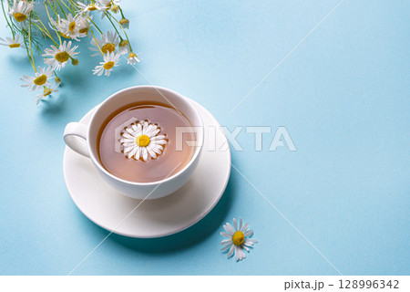Chamomile tea cup on blue background Chamomile tea cup on blue background 128996342