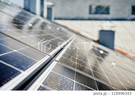 Solar photovoltaic panels on rooftop. Close up of solar batteries installed on top of modern house. Concept of alternative energy sources in modern life. Solar photovoltaic panels on rooftop. Close up of solar batteries installed on top of modern house. Concept of alternative energy sources in modern life. 128996383