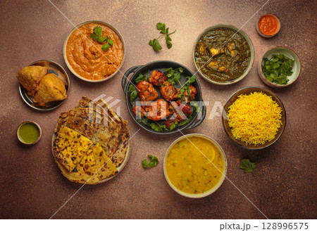 Traditional assorted Indian dishes top view on rustic brown background table. Cuisine of India 128996575