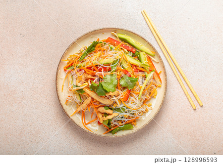 Delicious asian salad with rice noodles, chicken and vegetables, a healthy meal in oriental style Delicious asian salad with rice noodles, chicken and vegetables, a healthy meal in oriental style 128996593