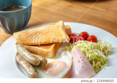 洋風の朝食セット、トーストと目玉焼き、ソーセージやサラダ添え 128996605