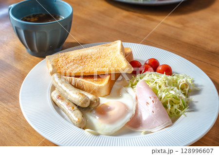 洋風の朝食セット、トーストと目玉焼き、ソーセージやサラダ添え 128996607