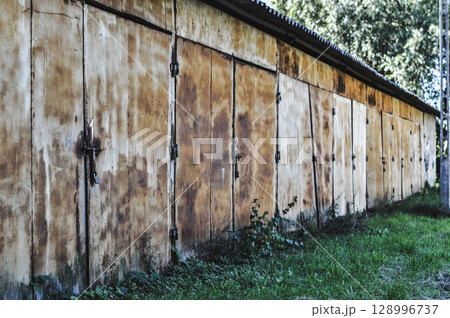 Old Abandoned Rusty Warehouse Buildings Amidst Greenery and Sunlight Old Abandoned Rusty Warehouse Buildings Amidst Greenery and Sunlight 128996737