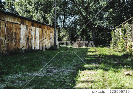 Old Abandoned Rusty Warehouse Buildings Amidst Greenery and Sunlight Old Abandoned Rusty Warehouse Buildings Amidst Greenery and Sunlight 128996739