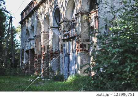 Old, Damaged Brick Building Bathed in Sunlight Amidst Green Trees Old, Damaged Brick Building Bathed in Sunlight Amidst Green Trees 128996751