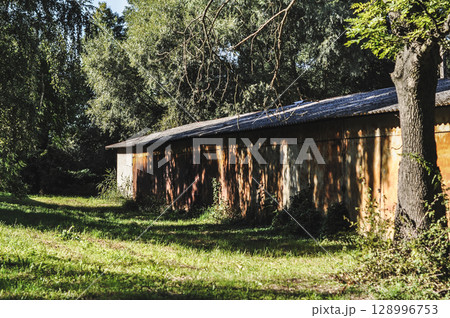 Old Abandoned Rusty Warehouse Buildings Amidst Greenery and Sunlight 128996753