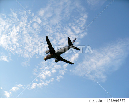A passenger plane against the blue sky takes off from the airport 128996871