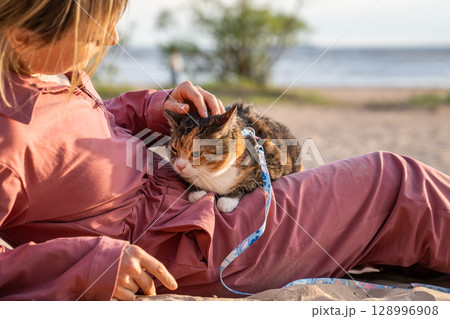 Uneasy displeased cat on owner lap petted soothed basking at beach. Nervous animal seek protection Uneasy displeased cat on owner lap petted soothed basking at beach. Nervous animal seek protection 128996908