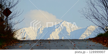 晩秋の北海道美瑛町から見た冠雪した十勝岳連峰と道ある風景 128999907