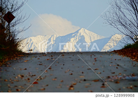 晩秋の北海道美瑛町から見た冠雪した十勝岳連峰と道ある風景 晩秋の北海道美瑛町から見た冠雪した十勝岳連峰と道ある風景 128999908
