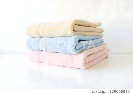 Soft Pastel Harmony A Stack of Fluffy Cream Blue and Pink Towels on White. 129000010