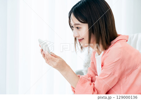 ソファでスマホを見る若い女性 ソファでスマホを見る若い女性 129000136
