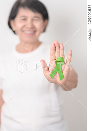 Elderly with light Green Ribbon for concept of May Celiac Awareness month, Lyme disease, September Lymphoma, Mental Health Awareness month and October Liver cancer. Health and world cancer day Elderly with light Green Ribbon for concept of May Celiac Awareness month, Lyme disease, September Lymphoma, Mental Health Awareness month and October Liver cancer. Health and world cancer day 129001682
