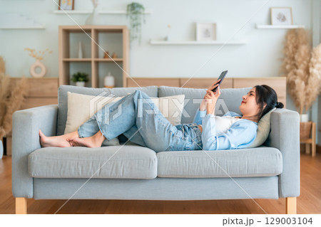 Happy cheerful positive young Asian woman on the phone at home 129003104