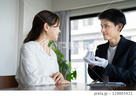 宝石の査定を受ける女性と鑑定士 129003411
