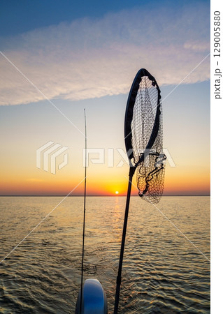 Fishing Net Silhouette Against a Stunning Sunset Over the Water Scenery. Perfect Holiday 129005880
