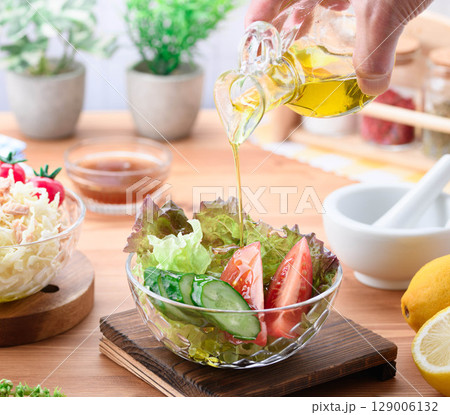 オリーブオイルをかけた彩り野菜サラダの食卓 129006132