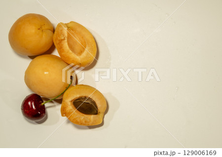 Ripe apricots and cherries on a beige background 129006169