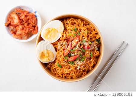 Top view of Spicy Korean dried instant noodles with boiled egg in kraft paper bowl and kimchi 129006198