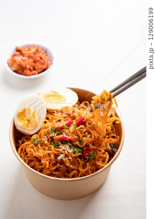 Spicy Korean dried instant noodles with boiled egg in kraft paper bowl and kimchi cabbage 129006199
