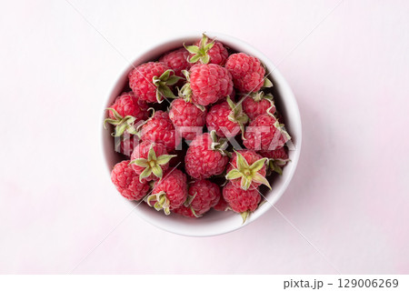 Top view of fresh ripe raspberry with leaf in bowl on pink background, Summer fruit 129006269