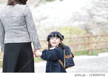 桜と入園式を迎えた3歳の女の子と母親 129006592