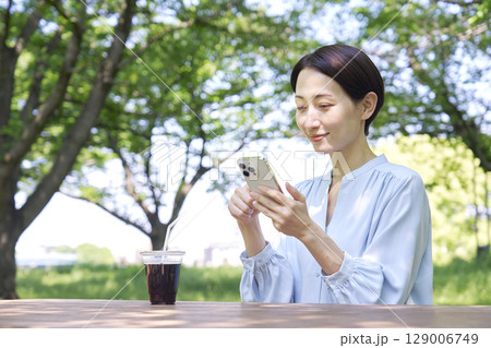 屋外でスマートフォンを使う女性 屋外でスマートフォンを使う女性 129006749