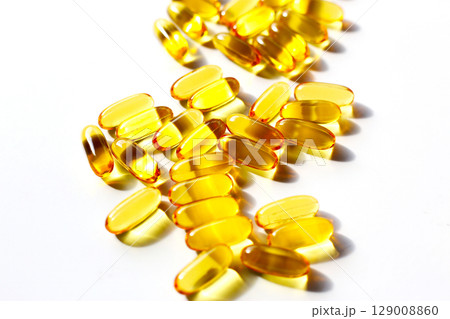 Golden fish oil capsules on white background. 129008860