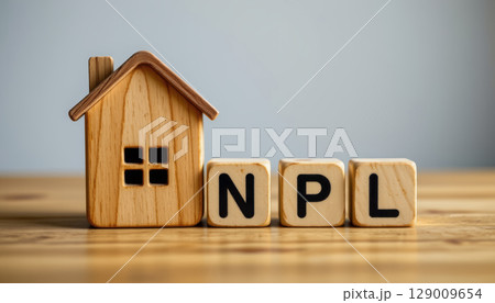 Wooden house model with letter blocks spelling NPL on wooden surface, concept of finance and real estate 129009654