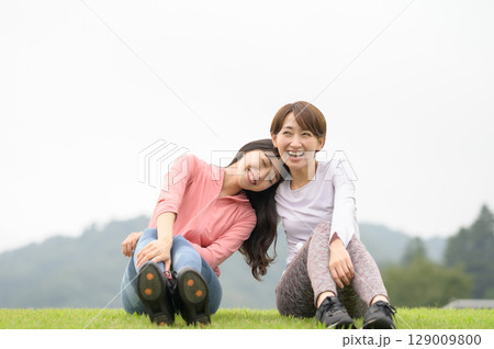 運動後に芝生の上で休憩する二人の女性 運動後に芝生の上で休憩する二人の女性 129009800
