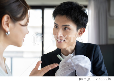 宝石の査定を受ける女性と鑑定士 129009910