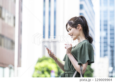 オフィス街でスマホを操作する若い女性 オフィス街でスマホを操作する若い女性 129009964