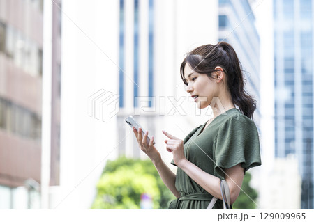 オフィス街でスマホを操作する若い女性 オフィス街でスマホを操作する若い女性 129009965
